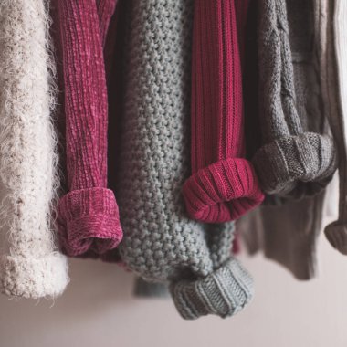 Katlanmış kolları olan örgü elbiseler kapalı mekanda asılı duruyor. Kış mevsimi. 