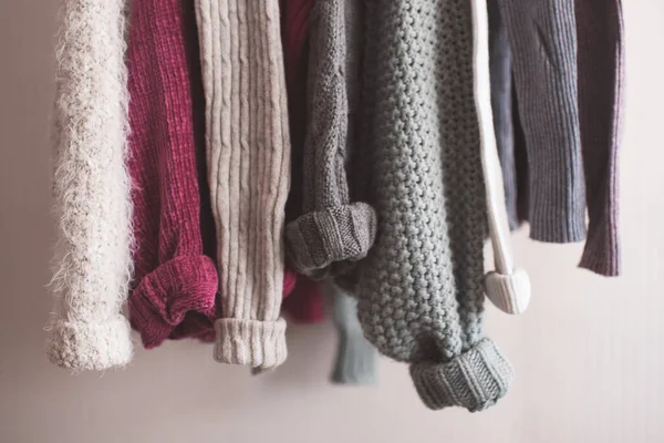 Katlanmış kolları olan örgü elbiseler kapalı mekanda asılı duruyor. Kış mevsimi. 