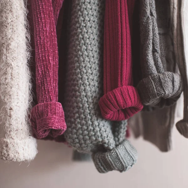 Katlanmış kolları olan örgü elbiseler kapalı mekanda asılı duruyor. Kış mevsimi. 