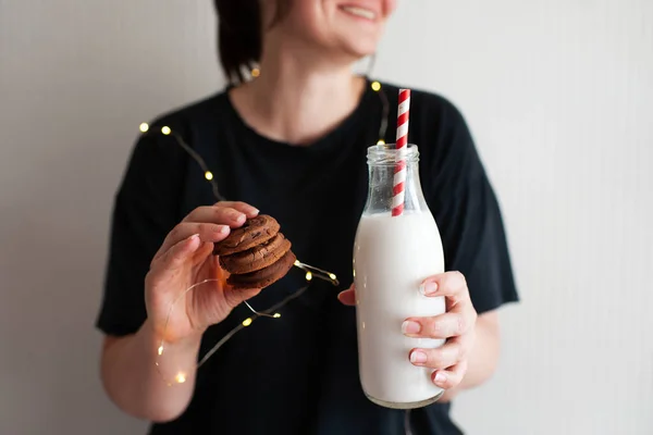 微笑的女人吃着巧克力饼干 把一瓶牛奶放在密室里 寒假季节 早上好 — 图库照片