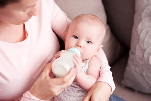 妈妈在房间里喂孩子 婴儿抱着奶瓶特写镜头中的牛奶 看着摄像机 健康营养 — 图库照片