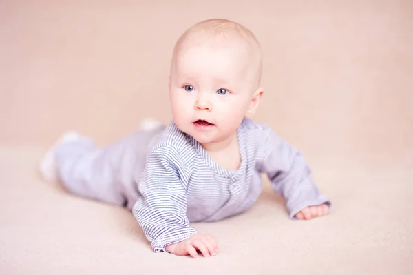 漂亮的女婴在床上爬过米色的背景 — 图库照片