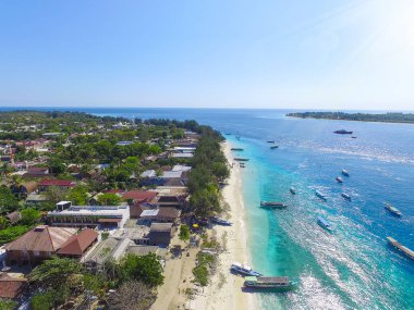 Endonezya 21 Haziran 2020: Beyaz kumlu plajlı tropikal ada ve mavi şeffaf su ve mercan resifleri. Hava saldırısı, sürat tekneleri, uzun kuyruklu botlar, Gili Trawangan Adası Endonezya