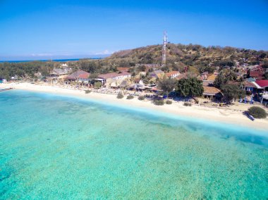 Endonezya 21 Haziran 2020: Beyaz kumlu plajlı tropikal ada ve mavi şeffaf su ve mercan resifleri. Hava saldırısı, sürat tekneleri, uzun kuyruklu botlar, Gili Trawangan Adası Endonezya