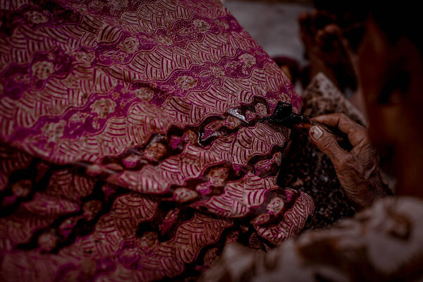 Indonesia June 18, 2020 : Batik, Close Up hand and canting, making Batik Tulis Indonesia. Canting is tool for drawing the texture on the fabric.