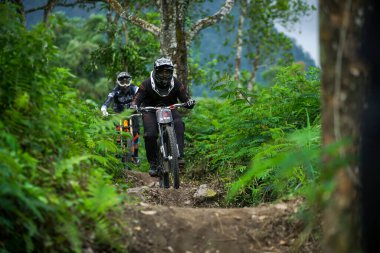 Endonezya 23 Haziran 2020: Tam donanımlı profesyonel motorcu yokuş aşağı bir dağ bisikleti sürüyor