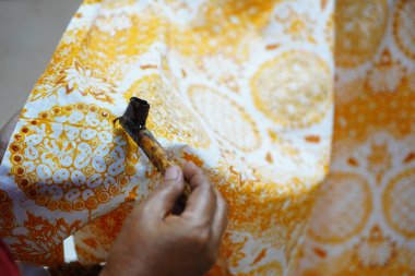 Surakarta, Endonezya 7 Ağustos 2020: Kumaşın altın batik arka planıyla Canting. Batik Tulis çizimi