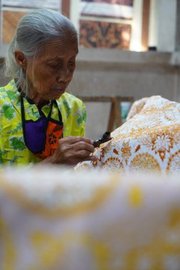 Surakarta, Endonezya 7 Ağustos 2020: Kumaşın altın batik arka planıyla Canting. Batik Tulis çizimi