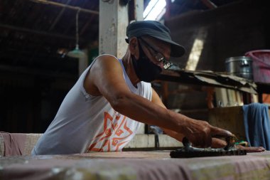 Surakarta, Endonezya 7 Ağustos 2020: Kumaşın altın batik arka planıyla Canting. Batik Tulis çizimi