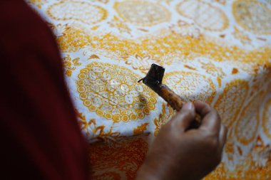 Surakarta, Endonezya 7 Ağustos 2020: Kumaşın altın batik arka planıyla Canting. Batik Tulis çizimi