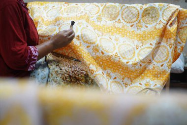 Surakarta, Endonezya 7 Ağustos 2020: Kumaşın altın batik arka planıyla Canting. Batik Tulis çizimi