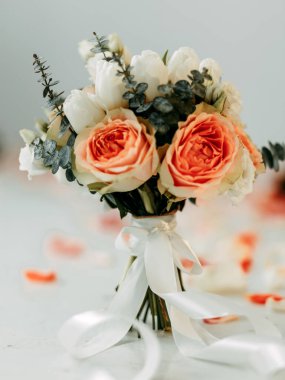 Gelinin buketi. Turuncu güller, beyaz laleler, yeşil dallar. Bir düğün için zarif, sofistike ve şık bir buket. Bir yaprak serpintisi.