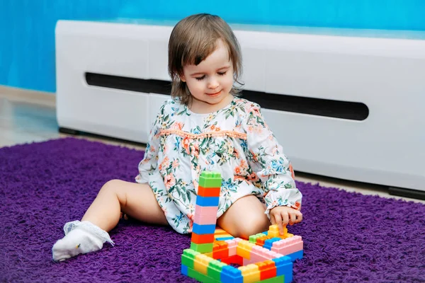 Little daughter plays with the constructor. Builds towers and a house. Folds up the pyramid. Child Game. Game room. Educational games.