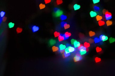 Yatay arkaplan. Siyah üzerine parlayan çok renkli kalpler. Praznik. Çelenk. Dekorasyon.