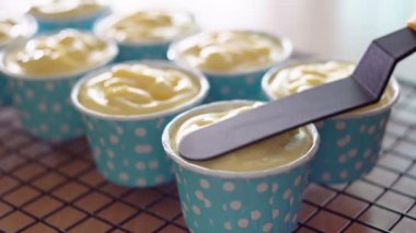 Şefler mavi bir cupcake üzerinde bir spatula yayılan krem peynir kullanıyor.