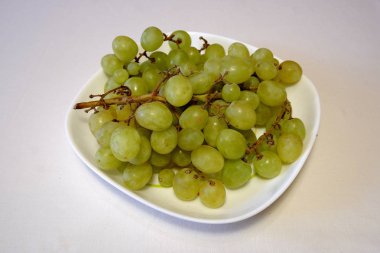 Beyaz kare tabakta yeşil üzüm demeti