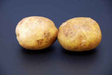 Koyu gri mat arka planda iki organik patates görünümü kapatın