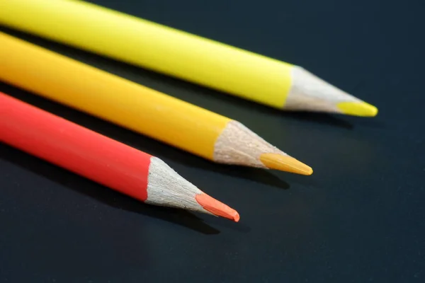 Three colored pencils on black background macro view — Stock Photo, Image