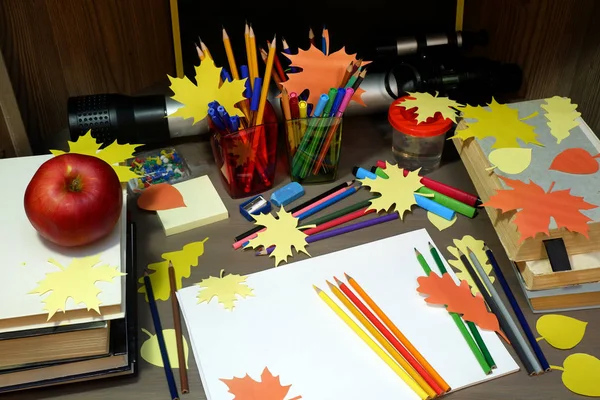 Back to school concept with empty sketchbook, colored pencils, stationary supplies and schoolbooks on brown wooden table with apple — Stock Photo, Image