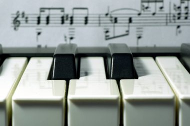 Arka plan makro görünümünde müzik notaları ile müzik klavyesi iki siyah tuşları, seçici odak 