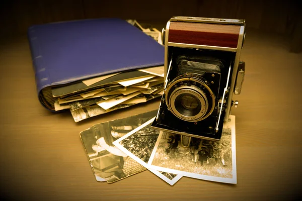 Retro old vintage outdated manual film camera circa 1940s, vintage photo album and old photos on wooden table. — Stock Photo, Image