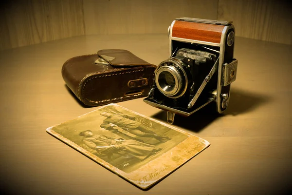 Retro old vintage outdated manual film camera circa 1940s, leather camera case and old vintage photo on wooden table. — Stock Photo, Image