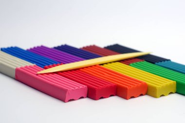 Çok renkli plastik çubuklar ve beyaz arka plan üzerinde heykel bıçak seti. Renkli plastik polimer kil seti.