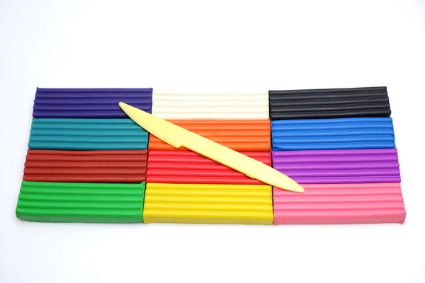 Bright multi-colored plasticine sticks and sculptural knife on white background — 스톡 사진