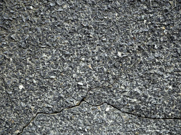 灰色の古いスタッコは小さな石で覆われています。石膏の上に深い亀裂が見える — ストック写真