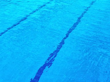 Temiz mavi suyu olan bir havuz. Havuzun dibinde, arkaplanı çapraz geçen paralel doğrular görülebilir.