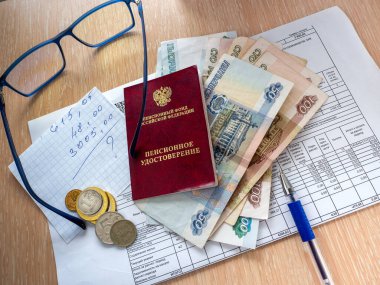 Faturada Rusya Federasyonu 'nun emeklilik sertifikası, Rus parası ve bir sayfa kağıt var. Masanın üzerinde bir kalem ve gözlük var..