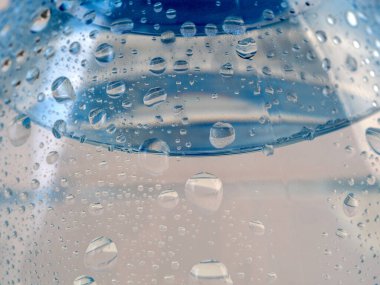 Plastik şişede su damlaları olan bir arka plan. Şişe temiz, berrak suyla dolu..