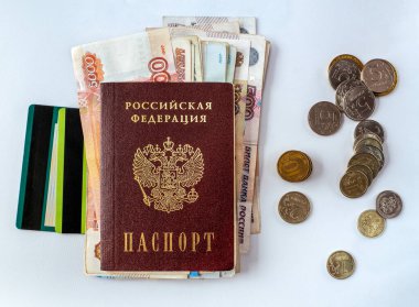 Banka ve kredi kartları, ruble faturaları Rus pasaportunun altında. Yakınlarda bozuk paralar var. Belgeler, para ve plastik kartlar beyaz arkaplanda izole edilmiş.