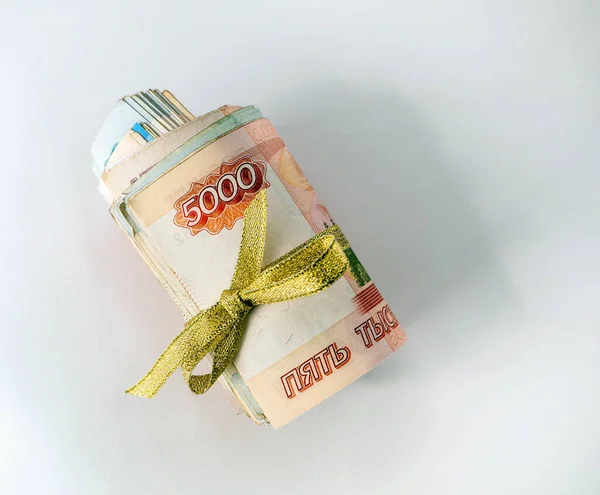 Birkaç Rus rublesi sarılıp altın bir kurdeleyle bağlanmış. Para beyaz arka planda yer almaktadır. Yakın plan. Rus Rublesi ile mali arkaplan.
