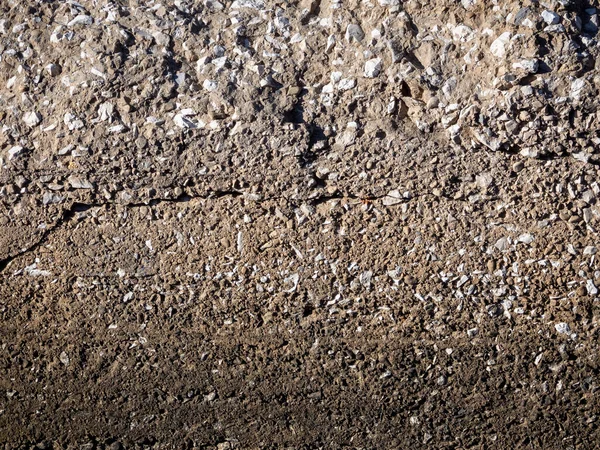 古い超硬合金製の壁の表面には 散在する小石 凹みが見られます 壁は太陽に照らされている 石の背景 テキストの空のスペース — ストック写真
