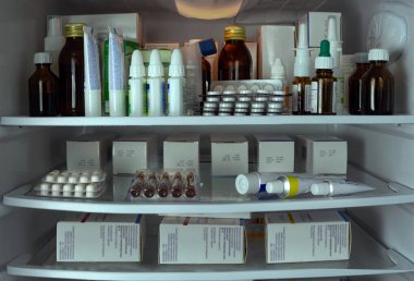 Buzdolabı rafları paketlerdeki ilaçlarla dolu. Kabarcıklar, kutular, tüpler, ilaç şişeleri düzgünce düzenlenmiş. Eczaneler, klinikler, hastaneler, işletmeler için tıbbi eğitim