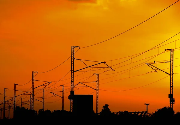 Silhouette High speed railway power line in perspective on spectacular intense orange sky, sunset or sunrise