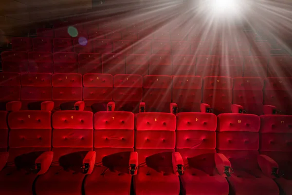 赤いアームチェアと明るいプロジェクターライトを備えた映画館 — ストック写真