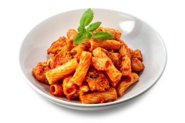 Domates soslu makarna, et parçaları ve beyaz tabaktaki taze fesleğen yaprakları kırpma yolu dahil olmak üzere beyaz tabaktaki makarna tortiglionisi makarna.