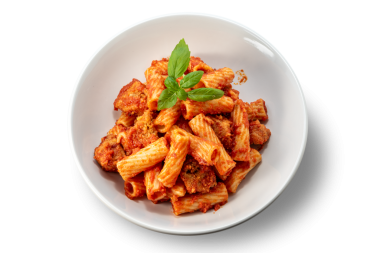 Domates soslu makarna, köfte parçaları ve beyaz tabakta taze fesleğen yaprakları.