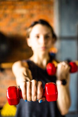 Genç kız spor yapıyor ve spor salonunda farklı egzersizler yapıyor. Spor sağlık demektir. Arka planda birçok spor malzemesi var. Sağlıklı bir yaşam tarzı teması..