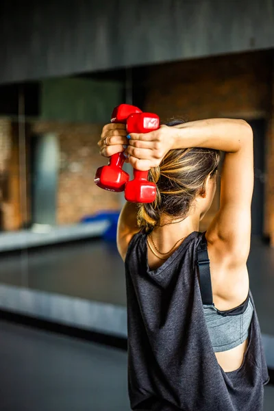 Young girl is doing fitness and different exercises in the gym.Sport is health. Many sports equipment on  e background.Themes of a healthy lifestyle.