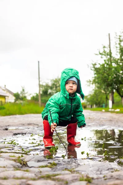 Ett Barn Liten Pojke Grön Jacka Och Röda Stövlar Leker — Stockfoto