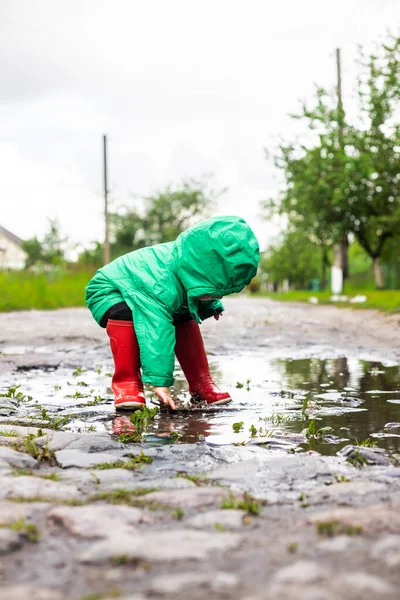 Ett Barn Liten Pojke Grön Jacka Och Röda Stövlar Leker — Stockfoto