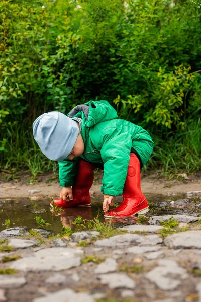 Ett Barn Liten Pojke Grön Jacka Och Röda Stövlar Leker — Stockfoto