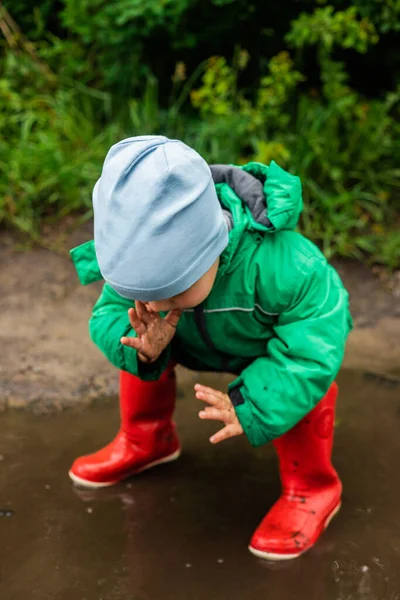 Ett Barn Liten Pojke Grön Jacka Och Röda Stövlar Leker — Stockfoto