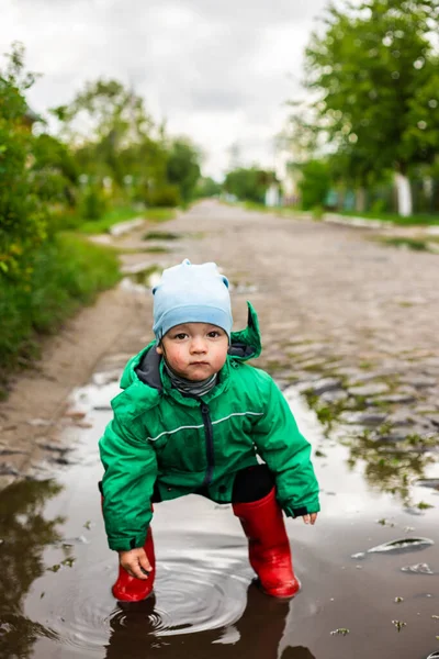 Een Kind Een Jongetje Een Groen Jasje Rode Laarzen Speelt — Stockfoto