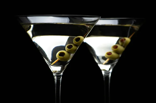 Закрыть коктейли мартини с оливками, изолированными на черном — стоковое фото
