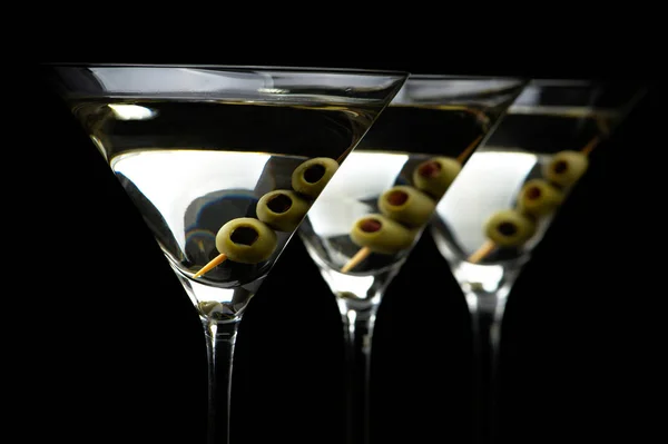 Nahaufnahme Martini-Drinks mit Stick mit Oliven auf schwarz — Stockfoto
