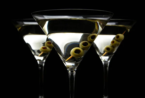 Primo piano Martini beve con olive su bastoncino isolato su nero Immagini Stock Royalty Free